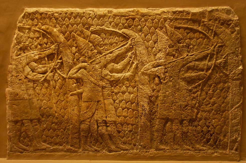 Heavy-armed archers in action. Assyrian, about 700-692 BC. From Nineveh, South-West Palace. These archers, the front one of whom is beardless, possibly an enuch, are each accompanied by a soldier whose duty it is to hold the tall shield in position and guard against any enemies who come too close. 