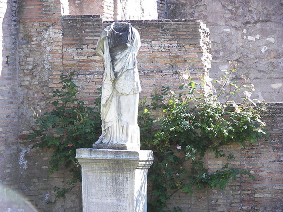 A beheaded statue at the House of the Vestals in the Forum Romanum in Rome. The name of the Vestal virgin has been erased, and only its initial, 'C' can be reconstructed.