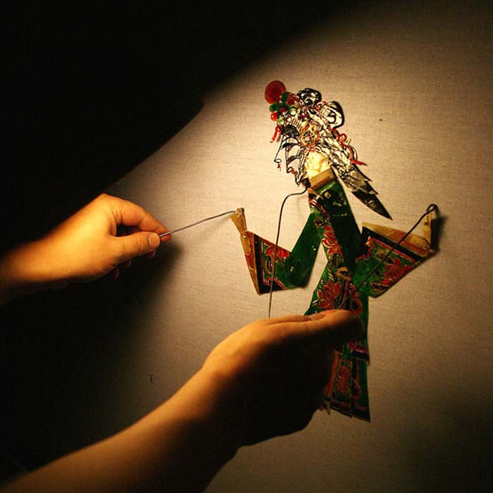Hands manipulate a shadow puppet.