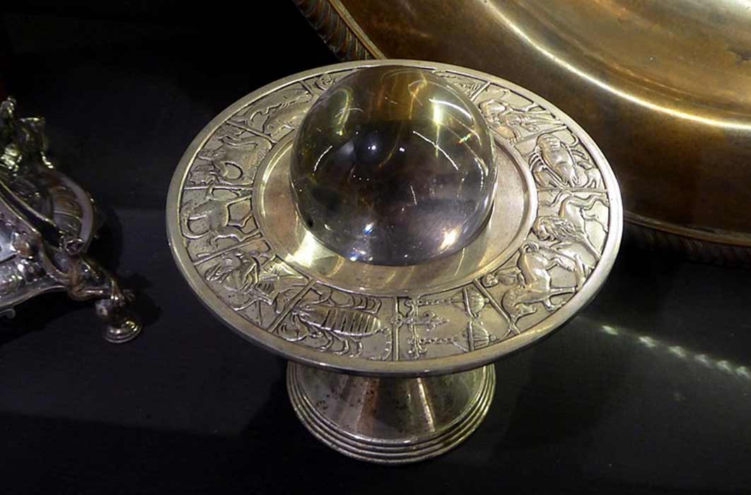 A crystal ball on a silver stand depicting the zodiac. Museum of Witchcraft and Magic in Boscastle, Cornwall. (Ethan Doyle White /CC BY-SA 4.0)