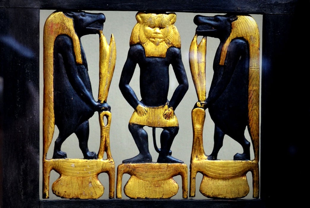 Detail from the richly decorated wooden chair or ‘throne’ of Sitamun, daughter and later wife of Amenhotep III, which was found in KV46. The image shows richly gilded images of Bes and two Tawaret figures; design by Anand Balaji (Photo credit: Heidi Kontkanen - Egyptian Museum, Cairo); Deriv.