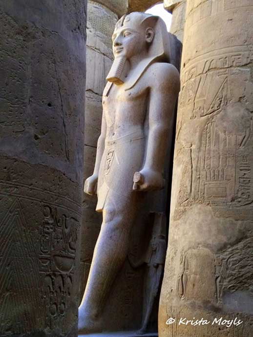 The grandiose and wealthy Karnak temple, dedicated to the Theban triad of Amun, Mut and Khonsu, is the largest religious building ever made. Covering about 200 acres (1.5 km by 0.8 km), it was a place of pilgrimage for nearly 2000 years. Here, an imposing sculpture of Ramesses II stands proud in the precincts of the temple.