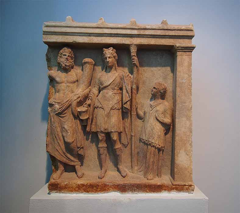 Votive relief of Dionysus and Hades with an adorant. (Fourth century BC)  Karystos, Archaeological Museum of Chalkida. (C messier/ CC BY-SA 4.0)