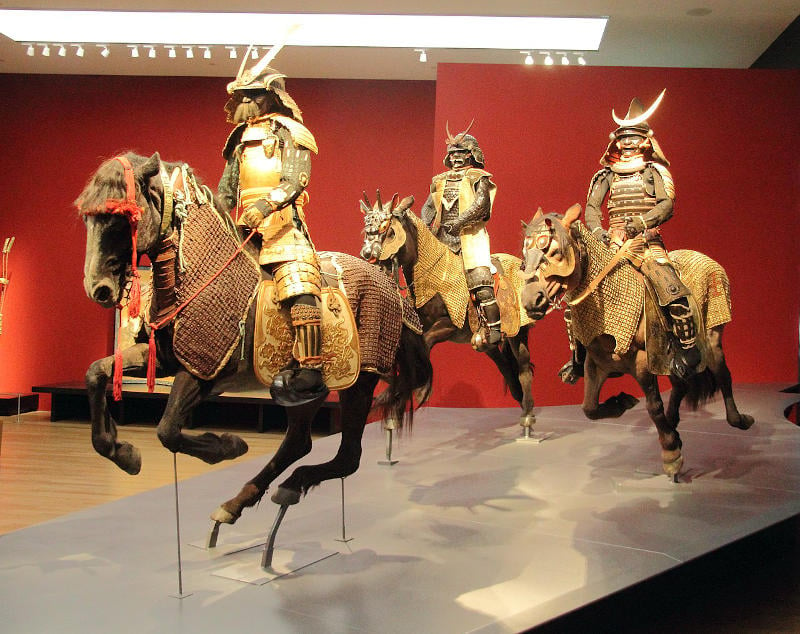 Display of samurai warriors riding horses into battle.